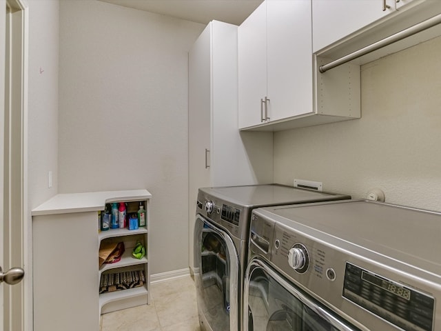 laundry area featuring washing machine and clothes dryer, light tile patterned floors, and cabinets