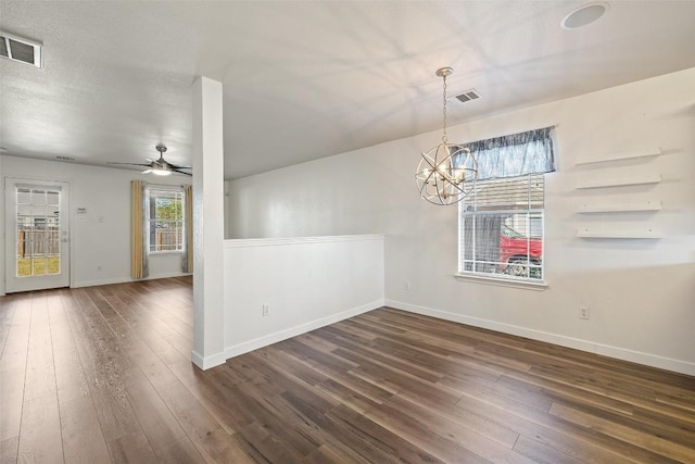 unfurnished dining area with dark hardwood / wood-style floors and ceiling fan with notable chandelier