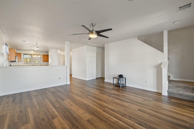 unfurnished living room with dark wood-type flooring and ceiling fan with notable chandelier