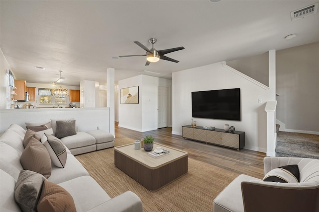 living room featuring ceiling fan with notable chandelier and light hardwood / wood-style floors