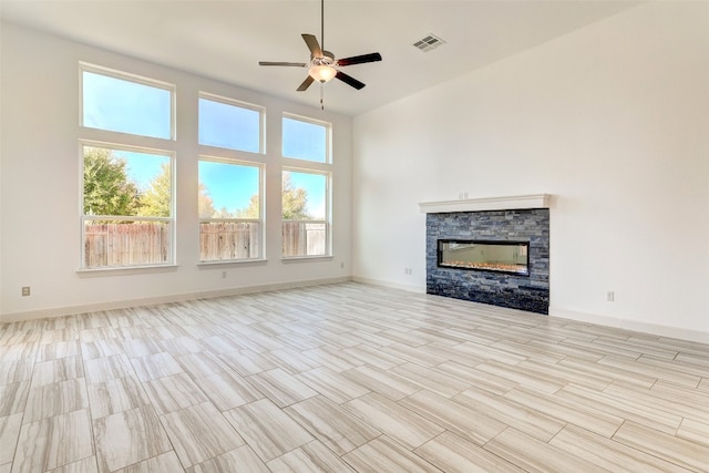 unfurnished living room featuring ceiling fan, a fireplace, and a high ceiling