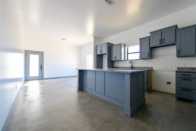 kitchen featuring tasteful backsplash, gray cabinetry, a kitchen island, and a healthy amount of sunlight