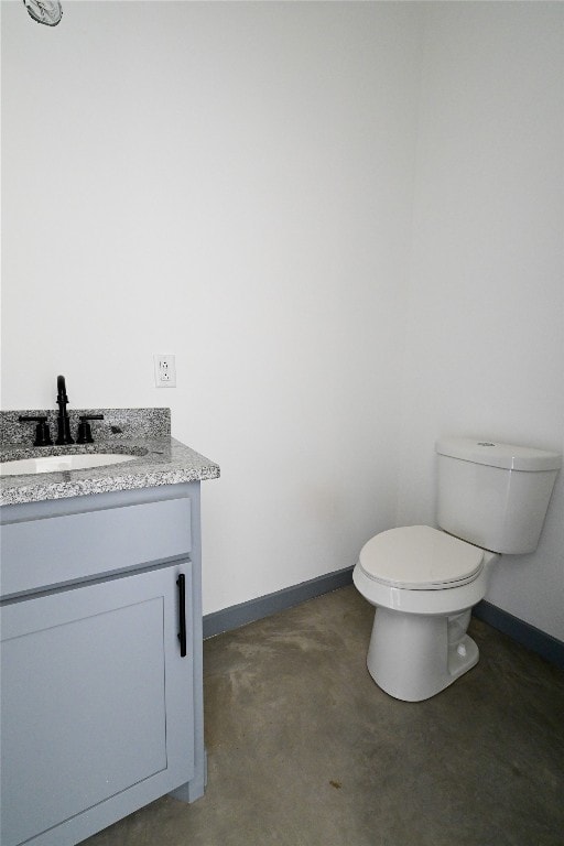 bathroom with vanity, toilet, and concrete floors