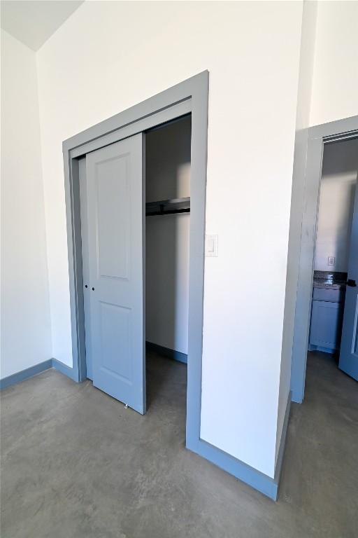 unfurnished bedroom with concrete flooring and a closet