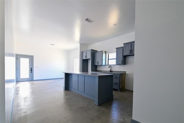 kitchen with tasteful backsplash, gray cabinetry, a center island, and sink