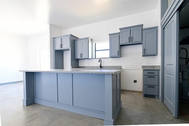 kitchen featuring backsplash, gray cabinets, a center island, and concrete floors