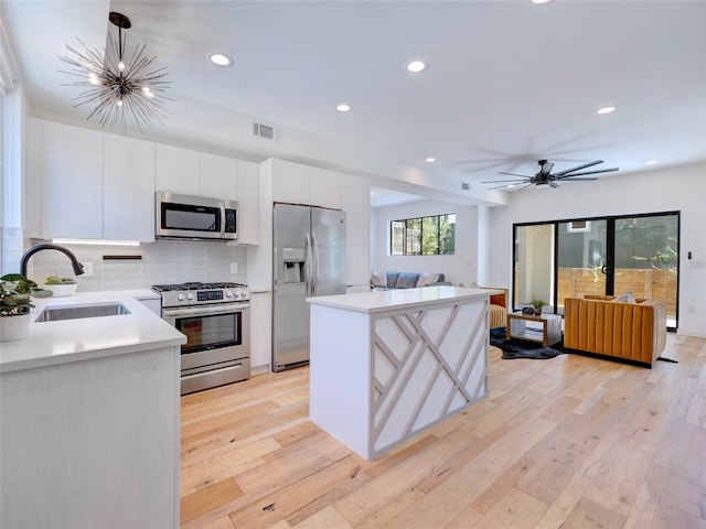 kitchen with white cabinetry, a center island, stainless steel appliances, light hardwood / wood-style flooring, and decorative light fixtures