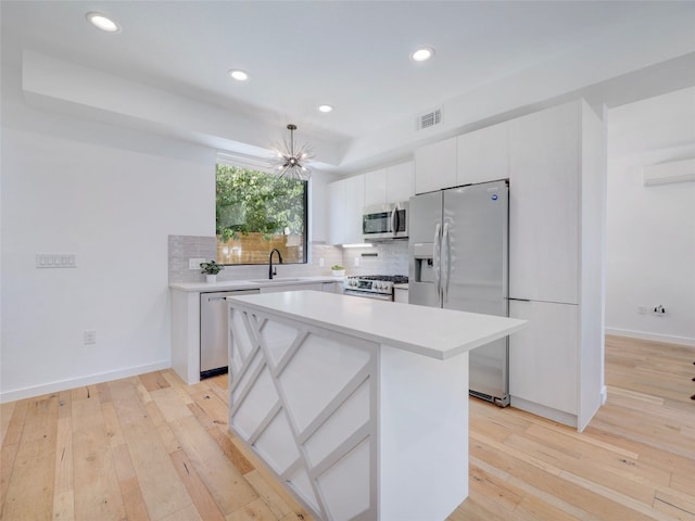 kitchen with white cabinetry, a kitchen island, stainless steel appliances, and light hardwood / wood-style floors