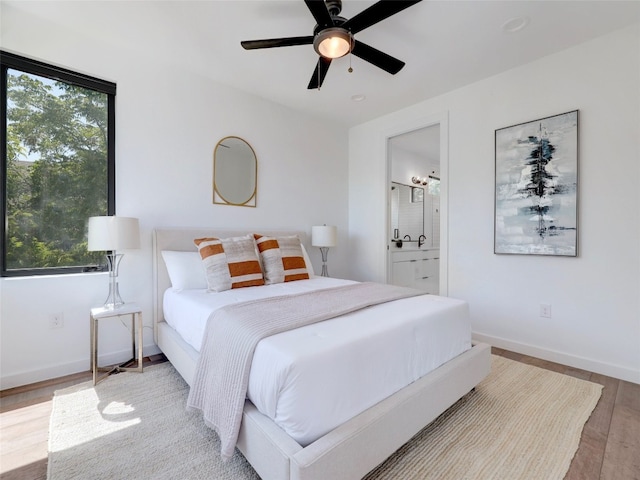 bedroom with hardwood / wood-style floors, connected bathroom, and ceiling fan