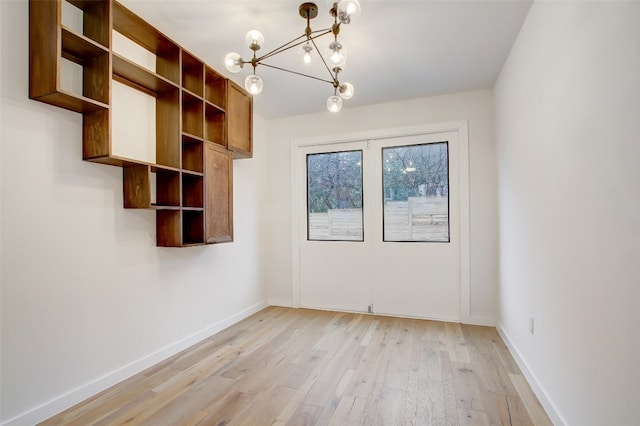 empty room featuring a chandelier and light hardwood / wood-style floors