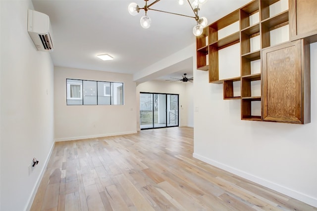 empty room with ceiling fan with notable chandelier, light hardwood / wood-style floors, and a wall unit AC