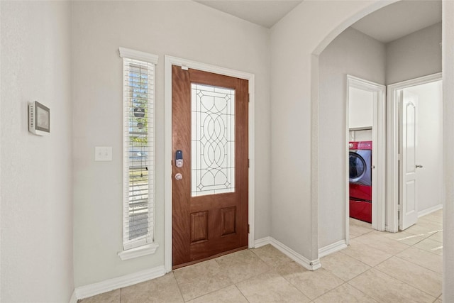 tiled entrance foyer featuring washer / clothes dryer and a healthy amount of sunlight