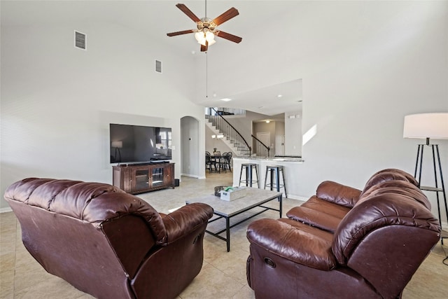 tiled living room with ceiling fan and high vaulted ceiling