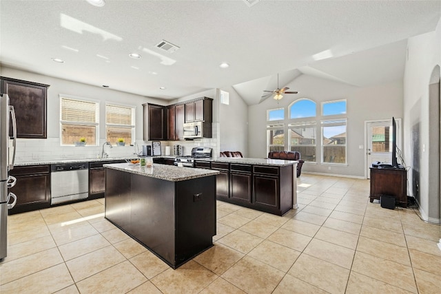 kitchen with lofted ceiling, a center island, stainless steel appliances, and a healthy amount of sunlight