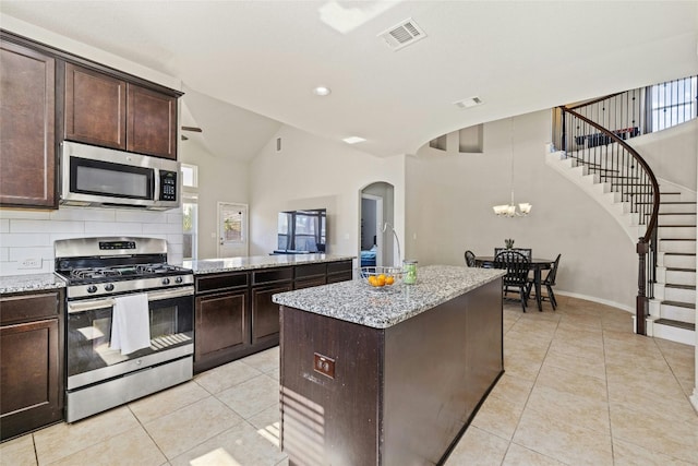 kitchen featuring dark brown cabinets, a kitchen island, light tile patterned floors, and appliances with stainless steel finishes