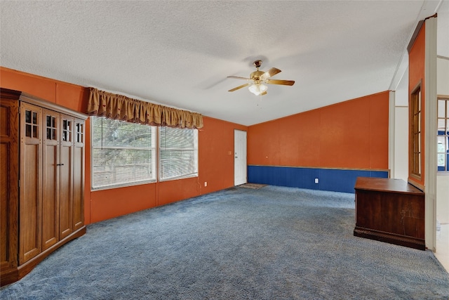 empty room featuring ceiling fan, dark carpet, and a textured ceiling