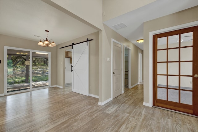 entrance foyer with a chandelier, a barn door, and light hardwood / wood-style flooring