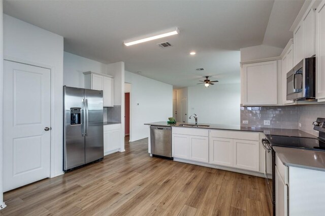 kitchen featuring decorative backsplash, appliances with stainless steel finishes, light wood-type flooring, sink, and white cabinets