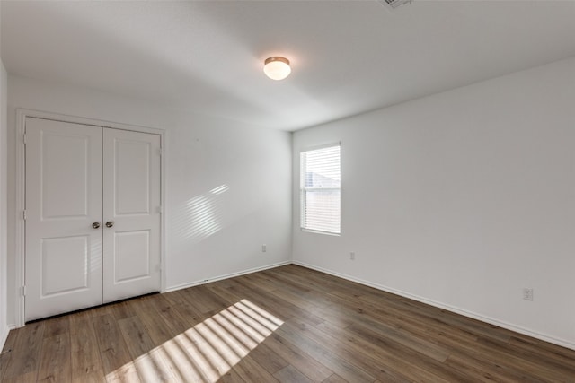 unfurnished bedroom featuring a closet and dark hardwood / wood-style floors