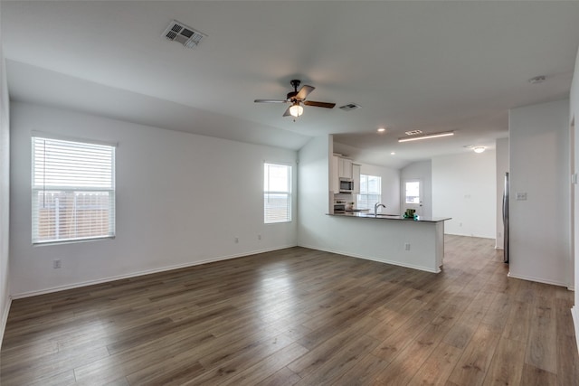 unfurnished living room with lofted ceiling, ceiling fan, dark wood-type flooring, and sink