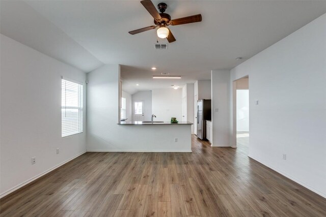 unfurnished living room featuring wood-type flooring, vaulted ceiling, ceiling fan, and sink