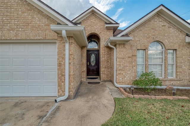 entrance to property featuring a garage and brick siding