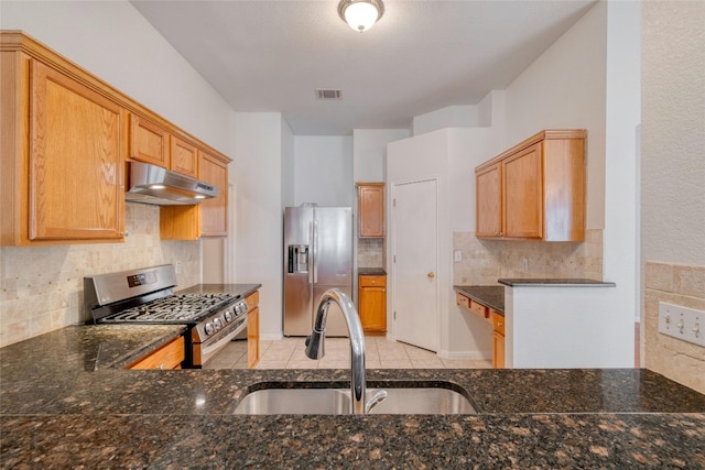 kitchen featuring under cabinet range hood, a sink, visible vents, appliances with stainless steel finishes, and dark stone counters