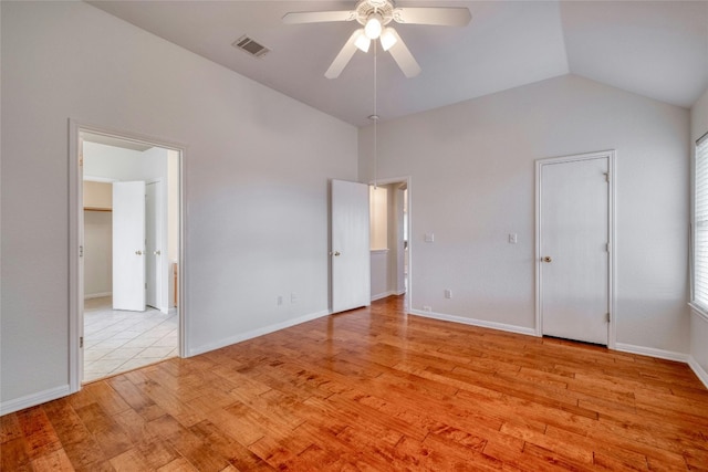 unfurnished bedroom featuring lofted ceiling, light wood-style floors, baseboards, and visible vents