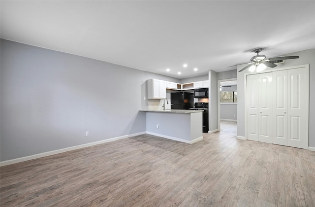 interior space with white cabinetry, ceiling fan, kitchen peninsula, black appliances, and light wood-type flooring