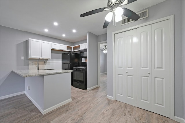 kitchen with black appliances, white cabinets, sink, light hardwood / wood-style flooring, and kitchen peninsula