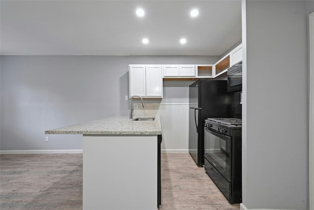 kitchen with light stone countertops, sink, white cabinetry, and black appliances