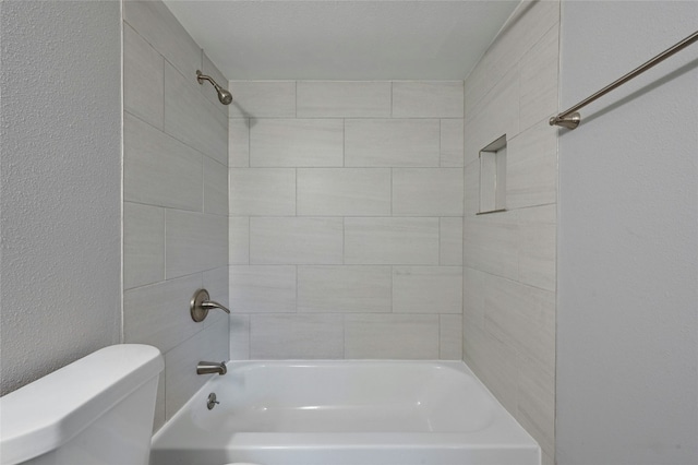 bathroom with tiled shower / bath combo and toilet