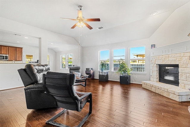 living room with ceiling fan, dark hardwood / wood-style flooring, lofted ceiling, and a fireplace