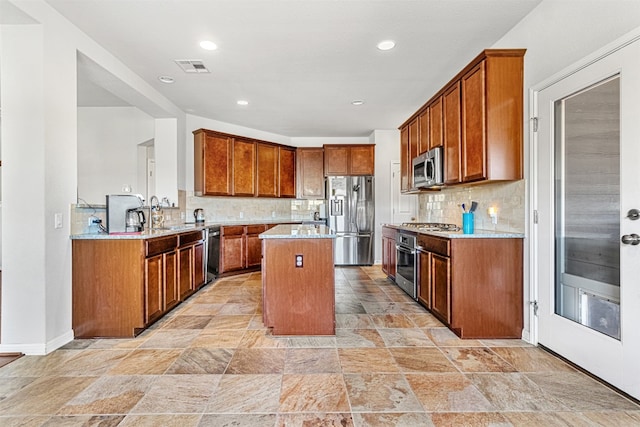 kitchen featuring light stone countertops, a center island, stainless steel appliances, and backsplash