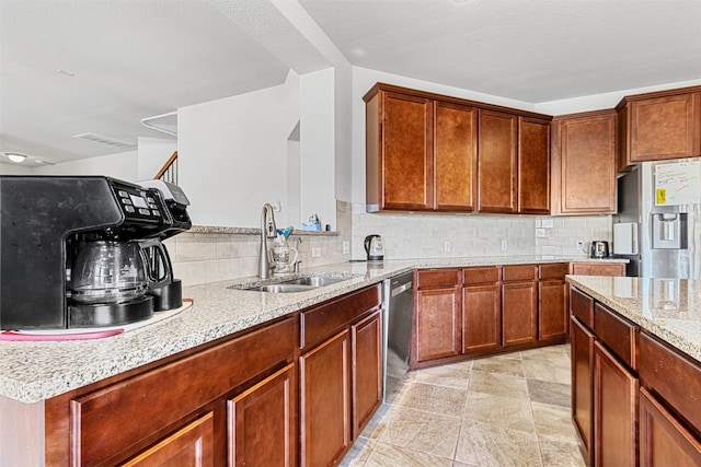 kitchen featuring sink, tasteful backsplash, light stone counters, a textured ceiling, and appliances with stainless steel finishes