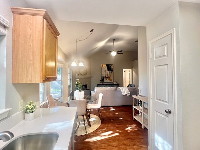 kitchen featuring lofted ceiling, sink, dark wood-type flooring, light brown cabinetry, and ceiling fan with notable chandelier