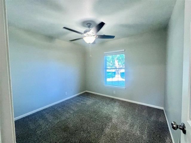 empty room featuring ceiling fan and dark colored carpet