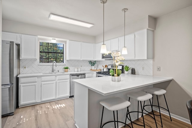 kitchen featuring pendant lighting, backsplash, stainless steel appliances, and white cabinetry