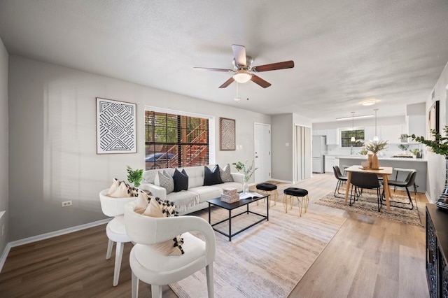 living room with a textured ceiling, light hardwood / wood-style flooring, and a healthy amount of sunlight