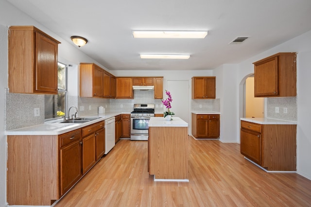 kitchen featuring stainless steel range with gas stovetop, a center island, white dishwasher, light hardwood / wood-style flooring, and sink