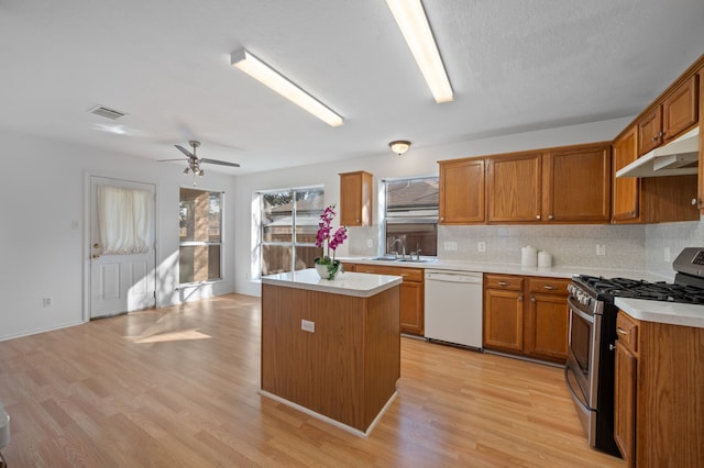 kitchen featuring dishwasher, gas stove, a kitchen island, sink, and light hardwood / wood-style flooring