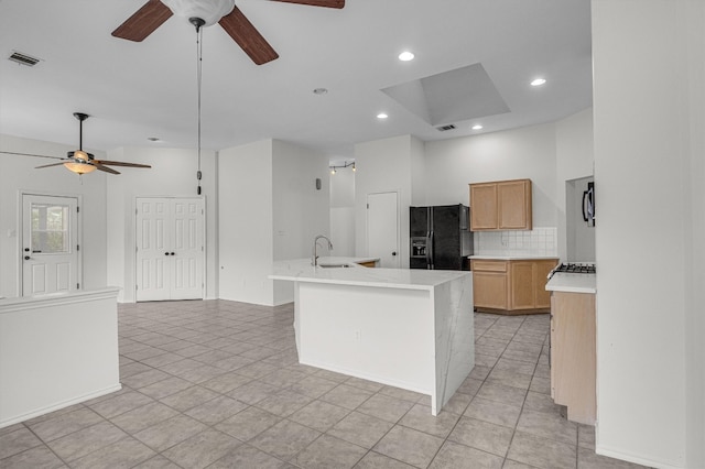 kitchen featuring black refrigerator with ice dispenser, sink, light brown cabinets, an island with sink, and light tile patterned flooring