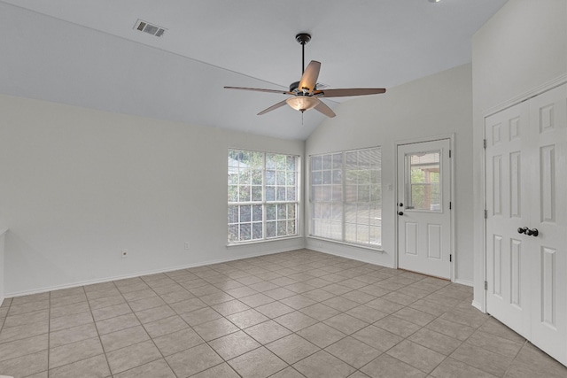 empty room with a healthy amount of sunlight, light tile patterned flooring, and vaulted ceiling