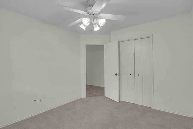 unfurnished bedroom featuring ceiling fan, light colored carpet, and a closet