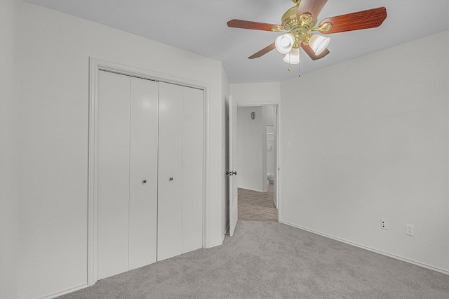 unfurnished bedroom featuring ceiling fan, a closet, and light colored carpet