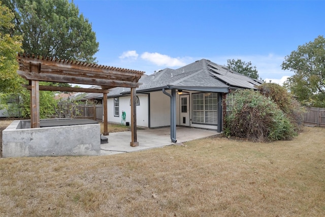 back of property with solar panels, a pergola, a patio, and a yard