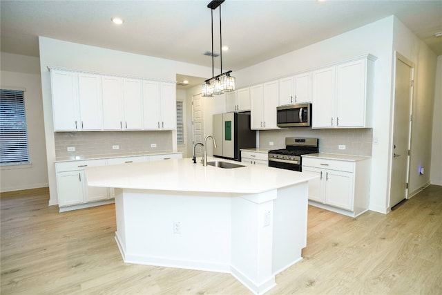 kitchen with sink, stainless steel appliances, white cabinetry, and an island with sink