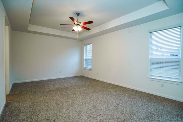 spare room with carpet flooring, a raised ceiling, and ceiling fan