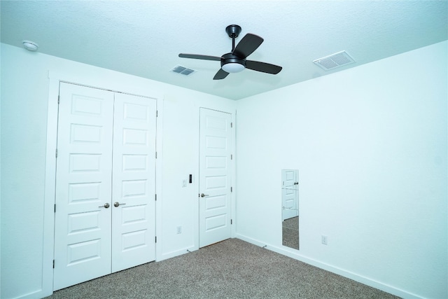 unfurnished bedroom with carpet flooring, a textured ceiling, a closet, and ceiling fan