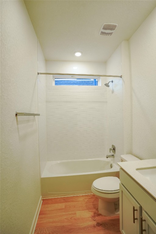 full bathroom featuring vanity, wood-type flooring, tiled shower / bath combo, and toilet